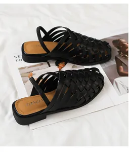 Detalle de sandalias de cuero negro tejidas a mano con tira elástica sobre revista de moda