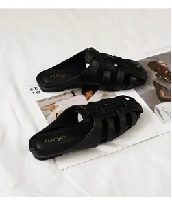 Primer plano de mules de cuero trenzado negro con diseño calado y suela plana elegante