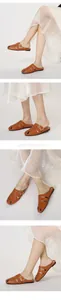 Detail view of caramel brown mule sandals with buckle straps and woven design