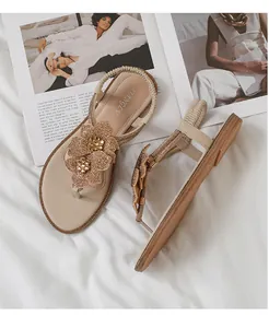 Close-up of sparkling rhinestone flowers and metallic beads on these flat beach sandals