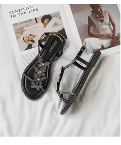Detail of black flat sandals with three sparkling rhinestone butterfly charms and buckle