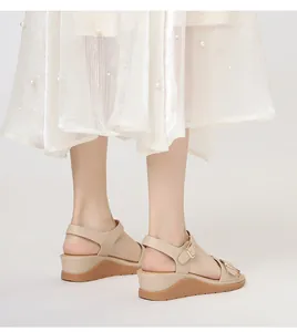 Dettaglio di sandali beige con zeppa con cinturini incrociati e fibbie in metallo