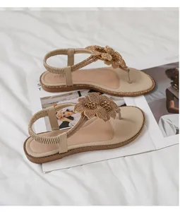 Close-up of beige flat sandals featuring 3D floral petals and sparkling rhinestone details