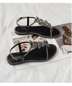 Macro detail of T-strap flat sandals with sparkling rhinestone butterfly design