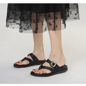 Detalle de chanclas negras con plataforma con hebillas doradas y tiras cruzadas