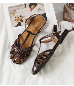 Detailaufnahme brauner Lackleder-Sandalen mit Flechtoptik und silberner Schnalle