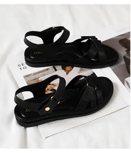 Detail der schwarzen flachen Sandalen mit rutschfestem Fußbett und Kreuzriemen-Design