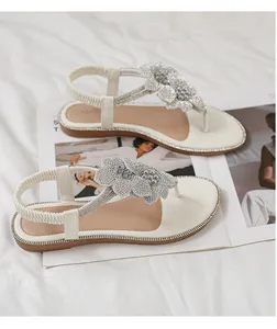 Detail of white beach sandals with rhinestone flowers and elastic back strap