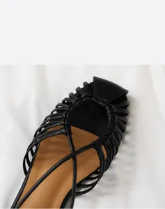 Detail of hand-woven black leather straps on the upper of a soft flat beach sandal