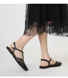 Close-up of black woven T-strap Roman flat sandals with elegant metal buckle detail