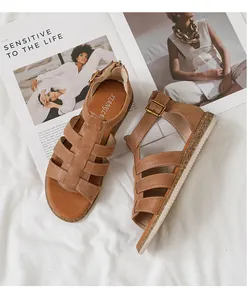 Nahaufnahme brauner flacher Sandalen mit Kreuzriemen und weißer Anti-Rutsch-Sohle