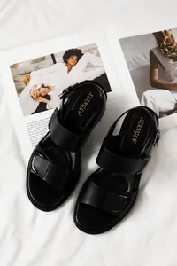 Detail schwarzer Bohemian-Sandalen mit doppelten Schnallenriemen auf Modezeitschriften