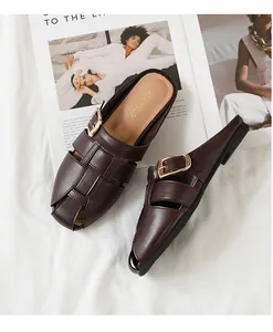 Detail of dark brown woven mule slipper with gold metal buckle on fashion magazine