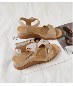 Dettaglio di sandali beige con zeppa con cinturini in pelle e fibbie in metallo dorato