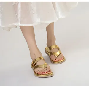 Detalle de sandalias de dedo doradas con tiras dobles y hebillas metálicas ajustables