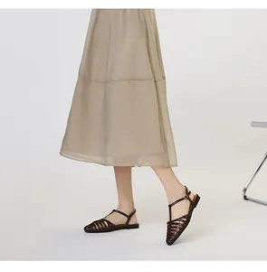 Detail of hand-woven dark brown leather T-strap sandals with buckle on a model