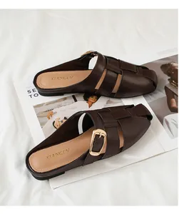 Detail of hand-woven dark brown leather mule with golden buckle on a fashion magazine