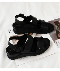 Detailaufnahme schwarzer Keilsandalen aus Leder mit doppelten Riemen auf hellem Grund