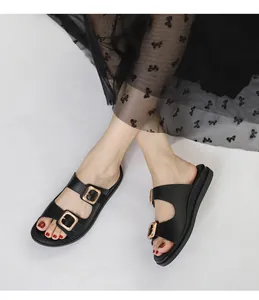 Dettaglio di sandali neri platform con fibbie dorate indossati con abito a fiori