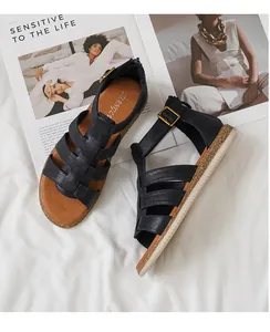 Detailansicht schwarzer flacher Römersandalen mit Kreuzriemen und weißer Gummisohle