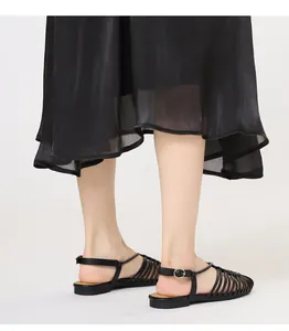 Detail of black woven strappy flat sandals with adjustable ankle buckle closure