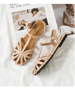 Nahaufnahme beiger geflochtener flacher Sandalen mit verstellbarer Knöchelschnalle