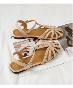 Nahaufnahme beiger geflochtener Sandalen mit feinem Flechtdetail und Knöchelriemen