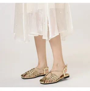 Detail of gold metallic cage sandals with square toe and ankle strap on a model