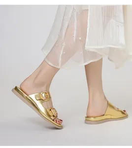 Eleganti sandali dorati a doppia fibbia abbinati a un abito bianco per un look estivo