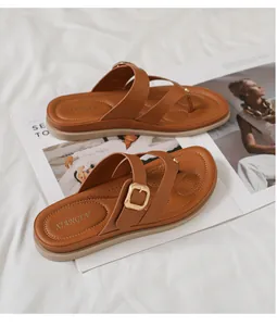 Detalle de sandalias de dedo marrón con hebilla dorada y suela interior ergonómica