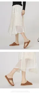 Brown leather thong sandals with wide strap shown on model with pearl skirt