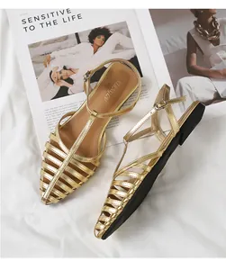 Top view of gold woven metallic flat sandals with cage design on white fabric
