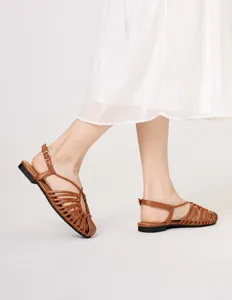 Brown woven flat sandals styled with a white dress for a soft summer beach look