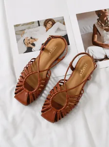 Close-up of woven brown flat beach sandals with hollow design and square toe on white cloth