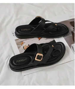 Primer plano de chanclas negras con tira ancha y hebilla redonda de metal dorado