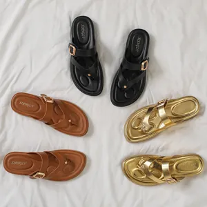 Chanclas elegantes de mujer con hebilla en negro, marrón y oro sobre tela blanca