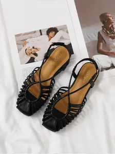 Close-up of woven cage toe design on black flat beach sandals with leather footbed