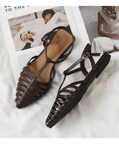 Detailed side view of dark brown woven strappy sandals on a white fabric background