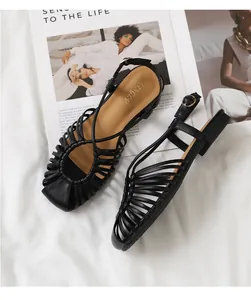 Close-up of black woven hollow flat sandals with adjustable buckle and soft brown insole