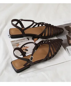 Detail of dark brown woven strappy roman flat sandals on a stylish magazine background