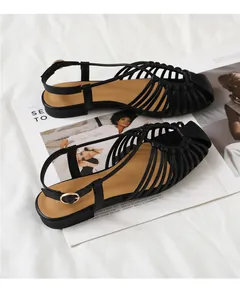 Detail of black woven cage flat sandals with adjustable heel strap and gold buckle