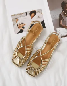 Macro detail of golden woven caged strap upper on square toe beach sandals