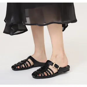 Detail of woven black flat mule with elegant gold buckle and pointed toe design