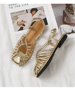 Detailed top view of gold woven strap flat sandals with a square toe and metal buckle