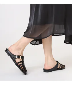 Detail of black woven flat mules with gold buckle and cross-strap cut-out design