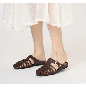 Detail of dark brown woven leather mule featuring a gold metal buckle on white background