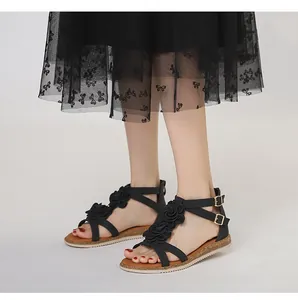 Close-up of bohemian flat sandals with 3D black rose decorations and gold buckles