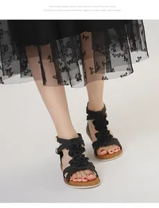 Detail of black bohemian flat sandals with 3D floral accents and ankle strap buckles