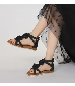 Detail of black flat sandals with 3D floral accents and golden adjustable buckle