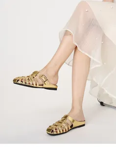 Detailed view of women's metallic gold woven cage sandals styled with a white dress